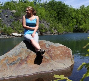 Cait Dickson, EPCAMR Watershed Outreach Intern, sitting on a rock in a flooded stripping pit in the Jim Thorpe Area.